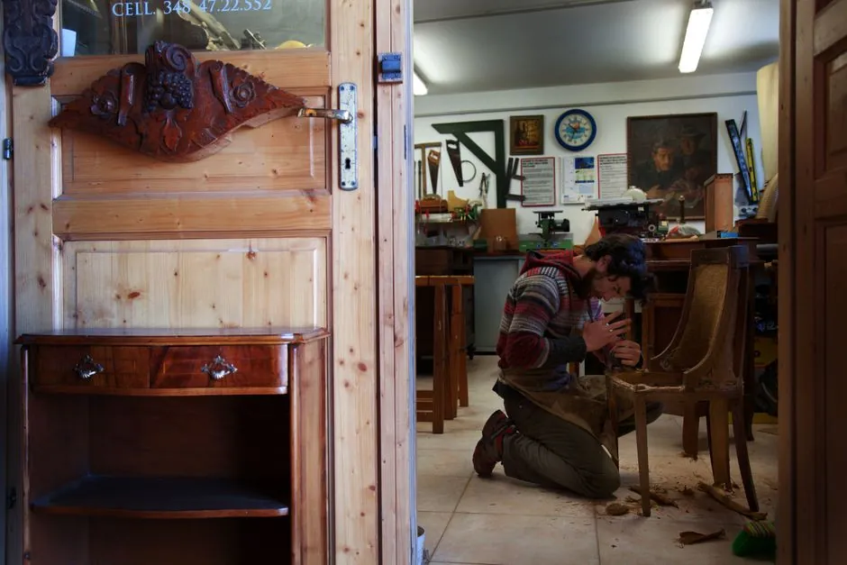 Menuisier en train de restaurer un meuble ancien en bois